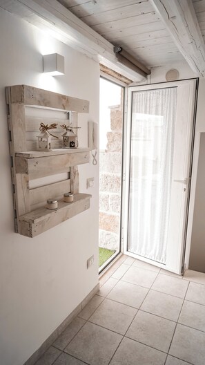 A room with a wooden wall-mounted shelf, a sliding glass door, and a tiled floor.