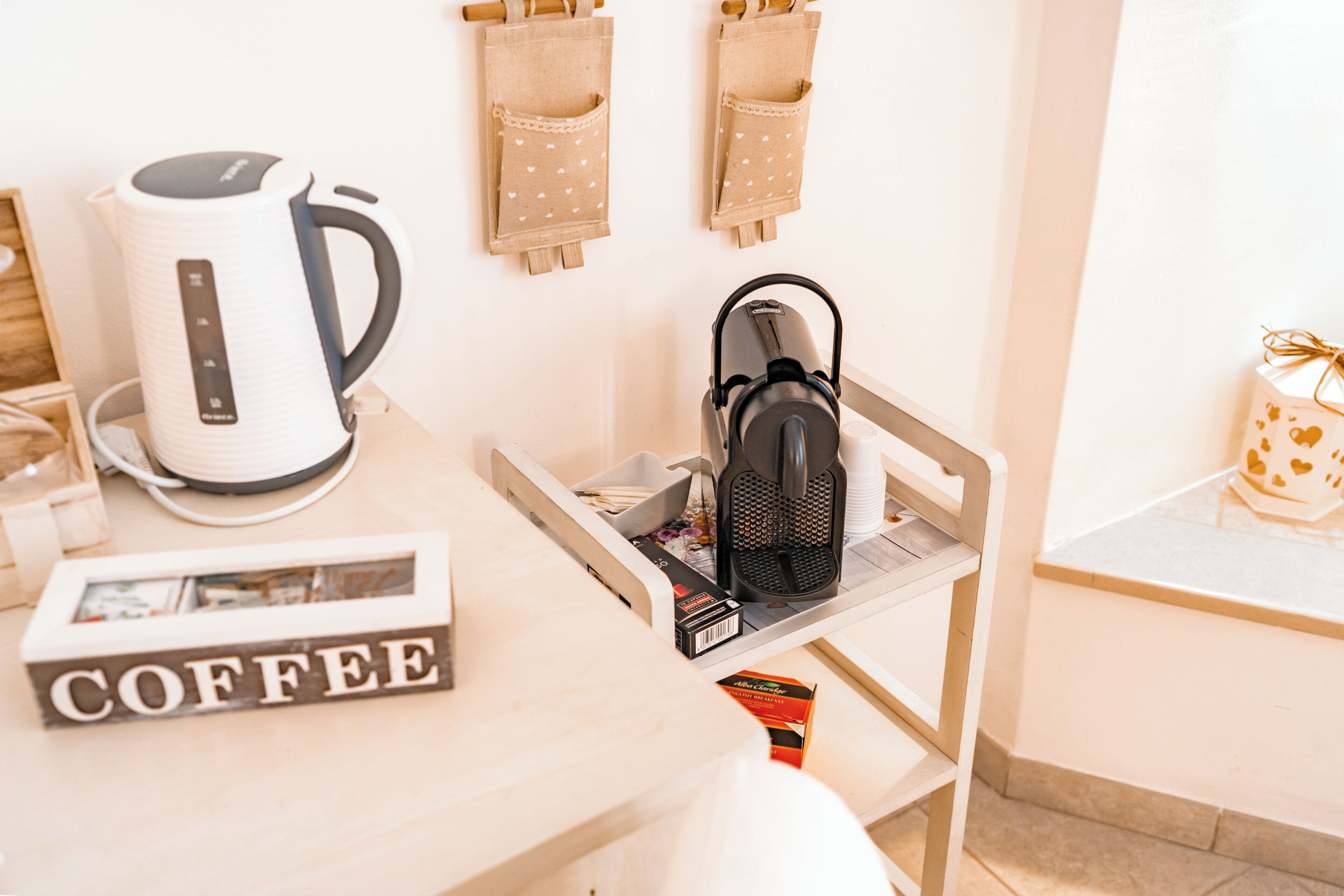 Una encimera de cocina con una cafetera, un hervidor y un cartel con motivos de café.