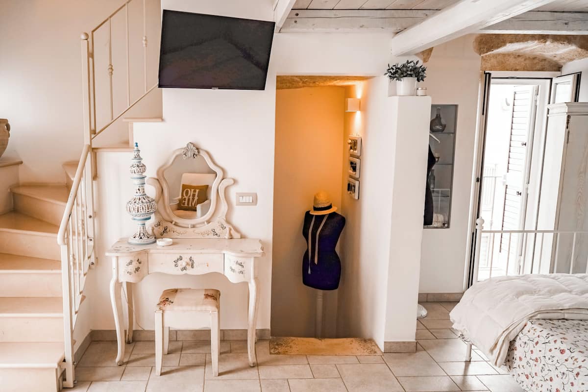 A staircase leading to a bedroom with a dresser, a mirror, and a mannequin.