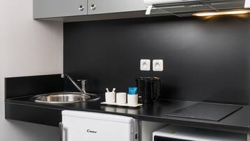 A modern kitchen with a built-in sink, a coffee maker, and a mini-fridge.