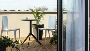 A balcony with two chairs, a small table, and a potted plant.