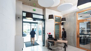 A modern lobby with a reception desk, a glass door entrance, and a view of the outside.