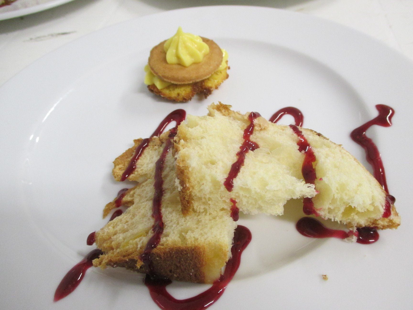 Une assiette à dessert avec une part de gâteau et une petite crêpe surmontée d’une cuillerée de crème.