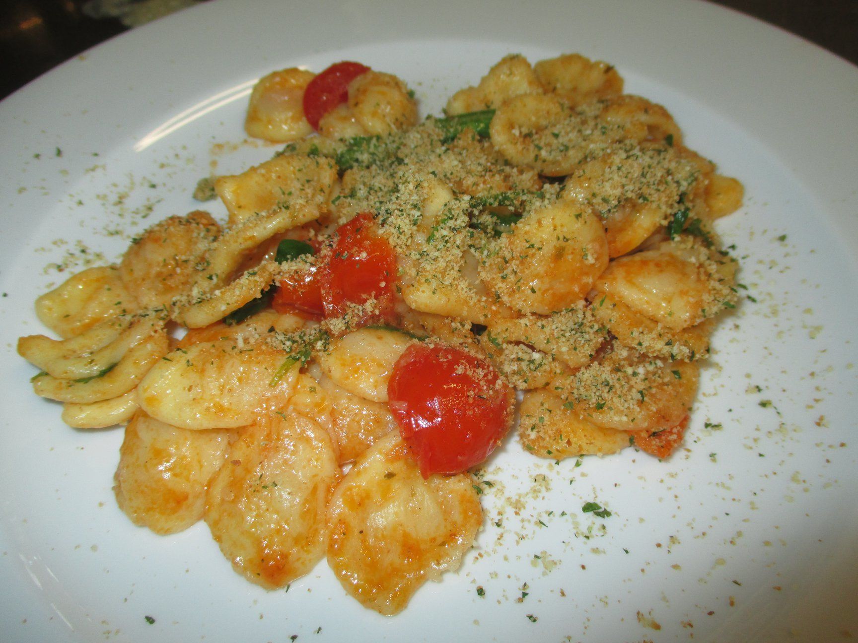 A plate of pasta with cherry tomatoes and a sprinkle of herbs.