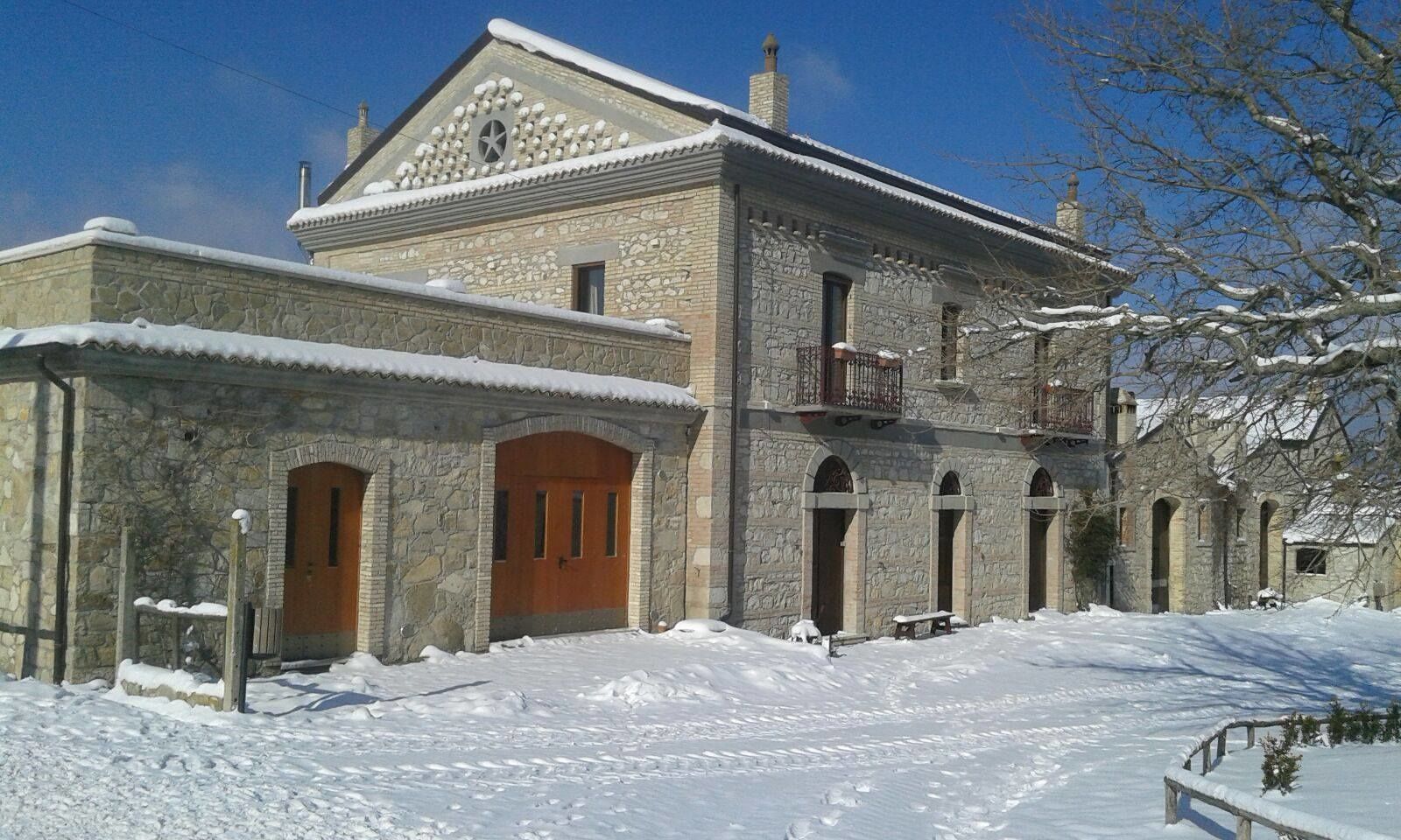 Un edificio in pietra con una porta in legno e finestre ad arco, immerso nella neve.