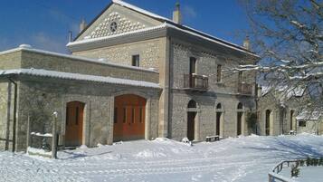 Un edificio in pietra con una porta in legno e finestre ad arco, immerso nella neve.
