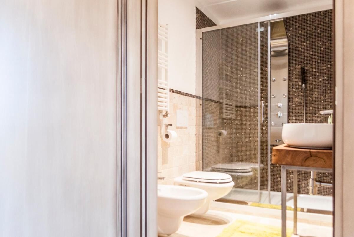 Un baño moderno con cabina de ducha de vidrio, dos inodoros y un lavabo con encimera de madera.