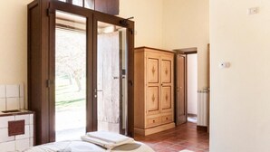Une chambre avec deux lits, une armoire en bois et une porte donnant sur un balcon.
