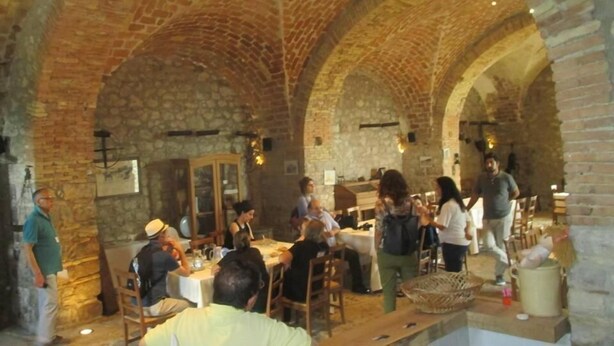 Un espace de restauration intérieur agrémenté d’arches en pierre et de murs en briques, avec des tables et des chaises à la disposition des clients.
