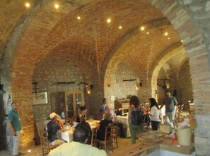 An indoor dining area with stone arches and brick walls, featuring tables and chairs for guests. - Masseria Salecchia (Bovino)