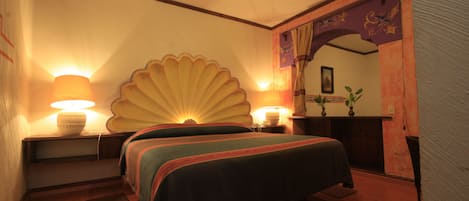 Quarto de hotel com duas camas, um painel decorativo grande e duas luminárias fixadas na parede.