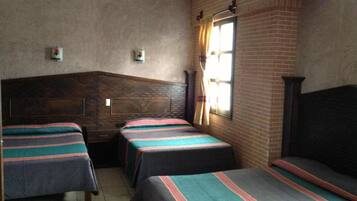 Una habitación con dos camas, una pared de ladrillo y una ventana con cortinas.