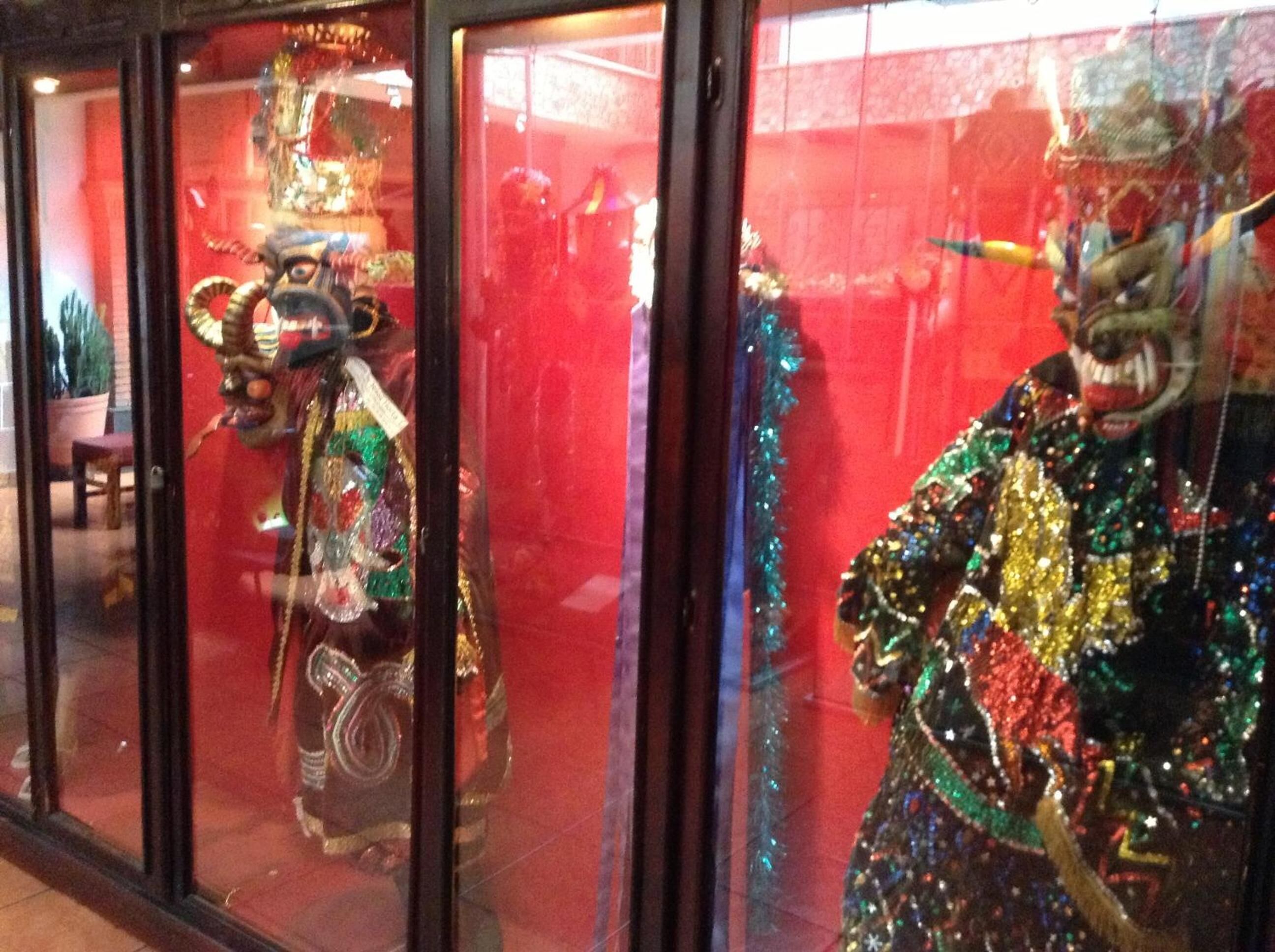A storefront with glass windows displaying mannequins in colorful costumes.