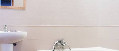 A bathroom with a white sink, a mirror, and a bathtub.