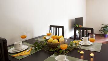 Une table à manger dressée avec des assiettes, des tasses et des verres, un panier de citrons et une bougie.