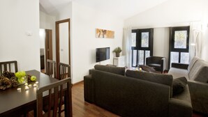 A modern living room with a dining area, featuring a sofa set, a TV, and a window with curtains. - Andorra4days Soldeu - El Tarter (Soldeu)