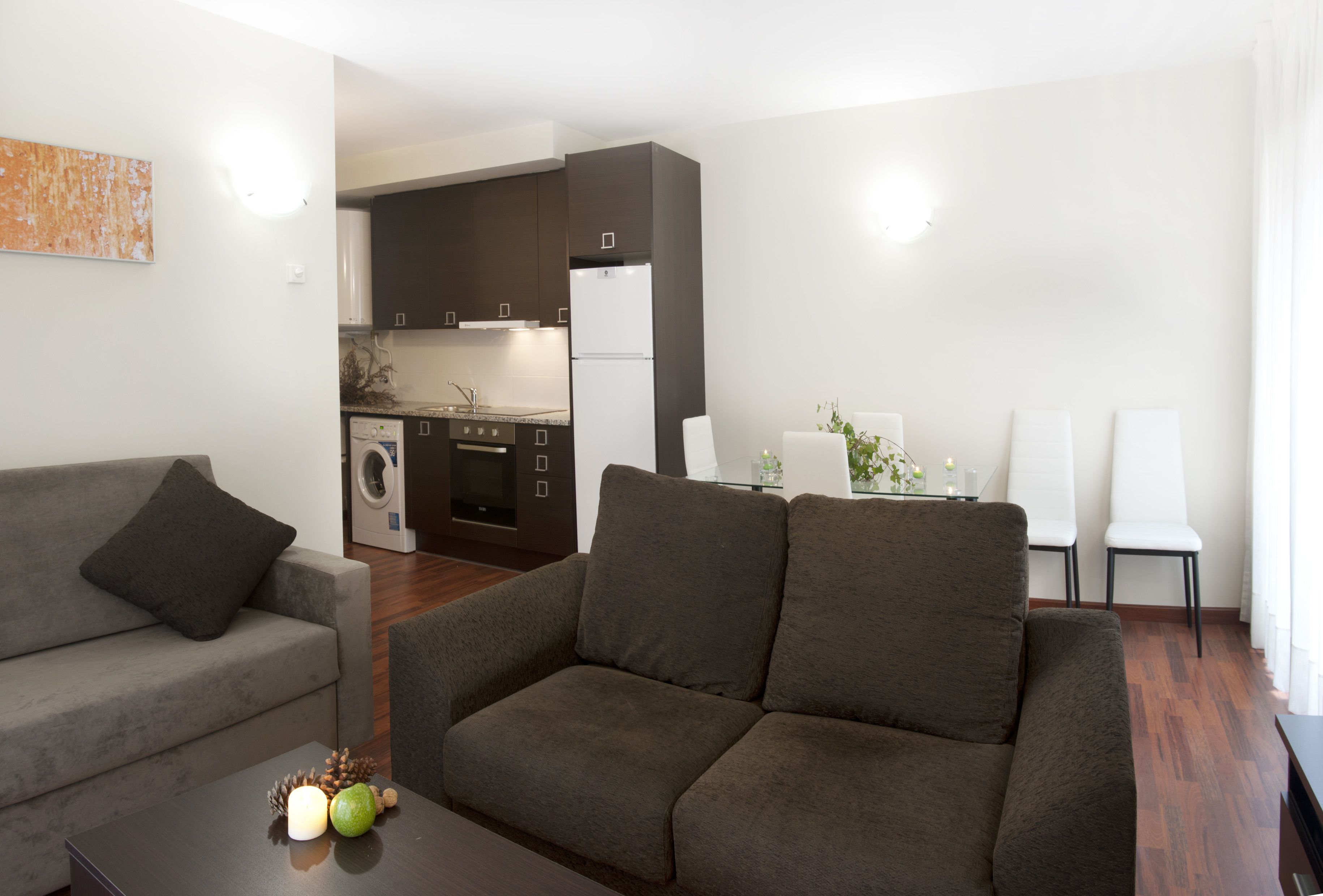 Una sala de estar moderna con un sofá gris y un comedor con sillas blancas.