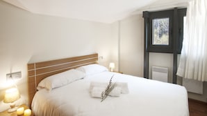 A neatly made bed with white linens and a decorative branch, a bedside lamp, and a window with curtains. - Andorra4days Soldeu - El Tarter (Soldeu)