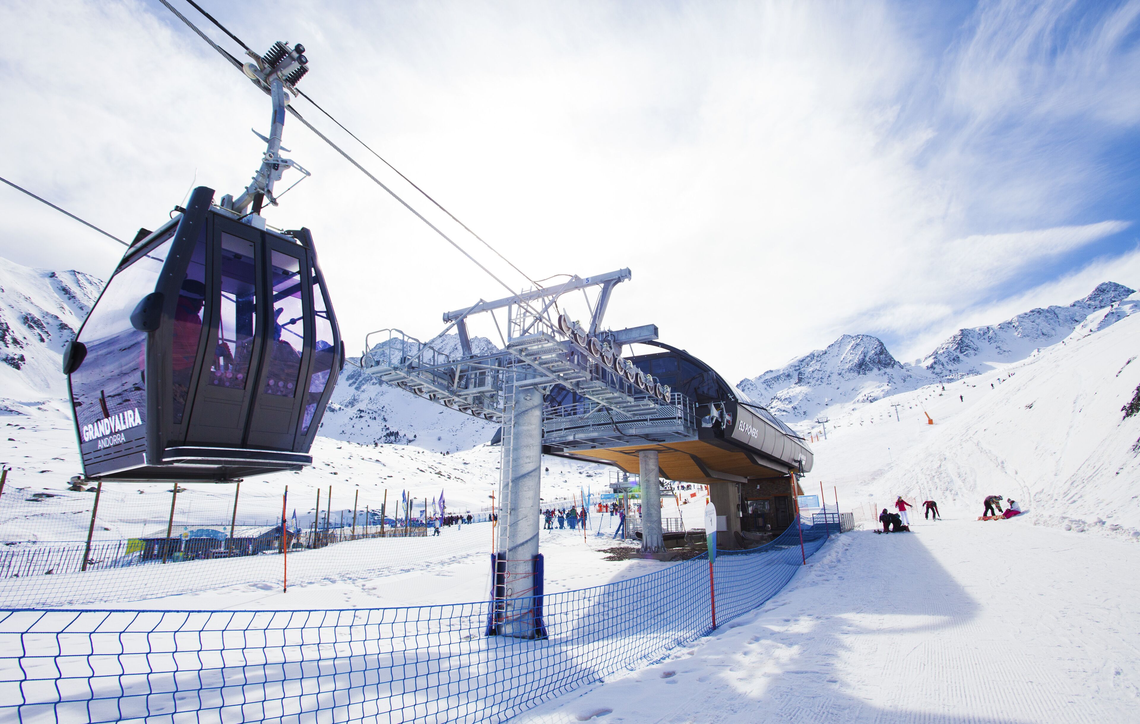 A ski lift with a cable car system and a snow-covered mountain backdrop.