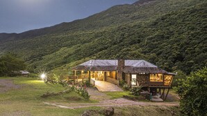 A rustic lodge with a thatched roof, surrounded by lush greenery and a mountain backdrop. - Cachoeira dos Borges Cabanas e Parque (Mampituba)