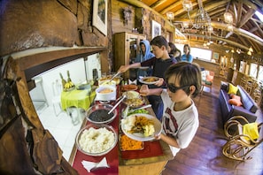 A rustic wooden interior with a dining area featuring a buffet table with various dishes. - Cachoeira dos Borges Cabanas e Parque (Mampituba)