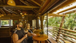 A wooden interior with a dining area, a bar, and a view of greenery outside. - Cachoeira dos Borges Cabanas e Parque (Mampituba)