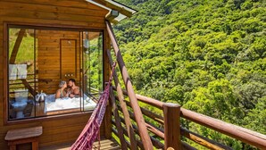 A wooden cabin with a glass door, a hammock, and a hot tub. - Cachoeira dos Borges Cabanas e Parque (Mampituba)