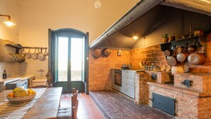 Eine rustikale Küche mit Backofen, Holzmöbeln und hängenden Töpfen.
