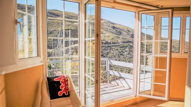 Una habitación con ventanas amplias que dan a un paisaje montañoso.