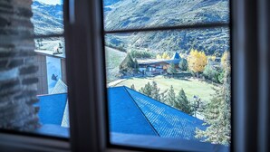 Vista desde una ventana a un paisaje montañoso con edificios y árboles.