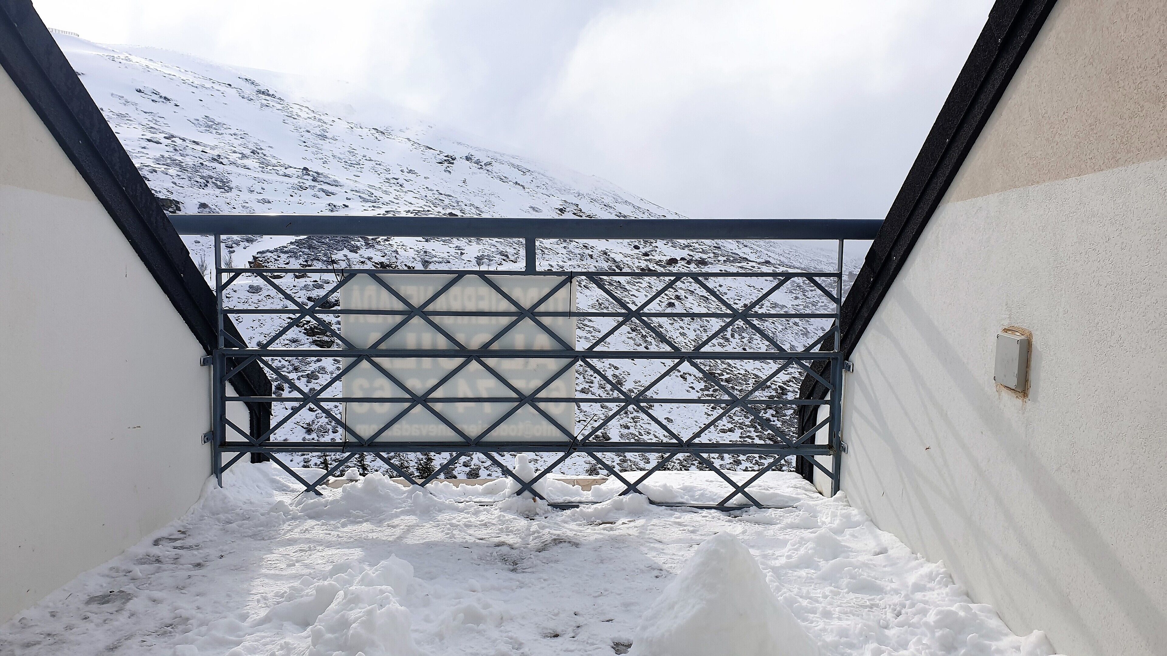 Un balcon enneigé, doté d’une rambarde en métal, d’où l’on peut admirer une montagne couverte de neige.