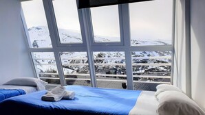 Una habitación con un ventanal que ofrece vistas a un paisaje montañoso nevado.
