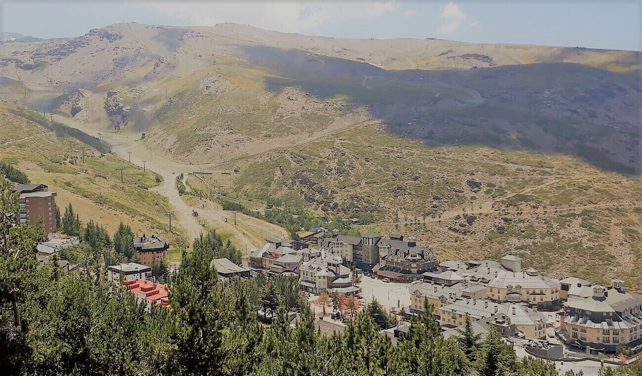 Un pueblo enclavado en un valle con terreno montañoso al fondo.
