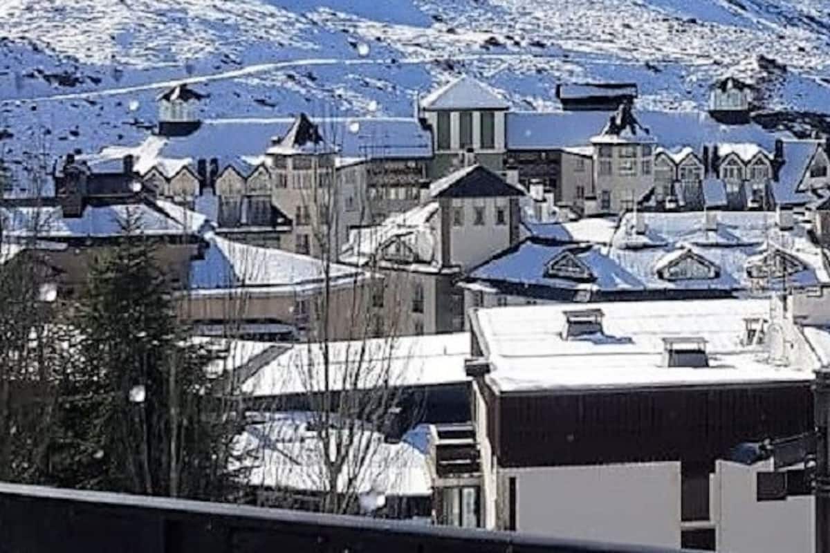 Uma cidade coberta de neve, com edifícios e uma montanha ao fundo.