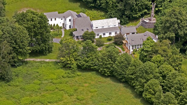 Une vue aérienne d’un vaste domaine comprenant plusieurs bâtiments, entouré d’une végétation luxuriante et d’arbres.