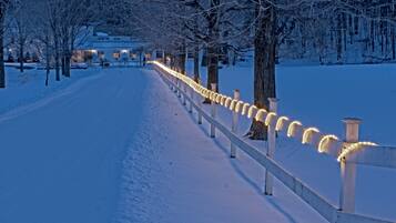 Uma trilha coberta de neve, ladeada por corrimãos iluminados, conduzindo a um edifício.