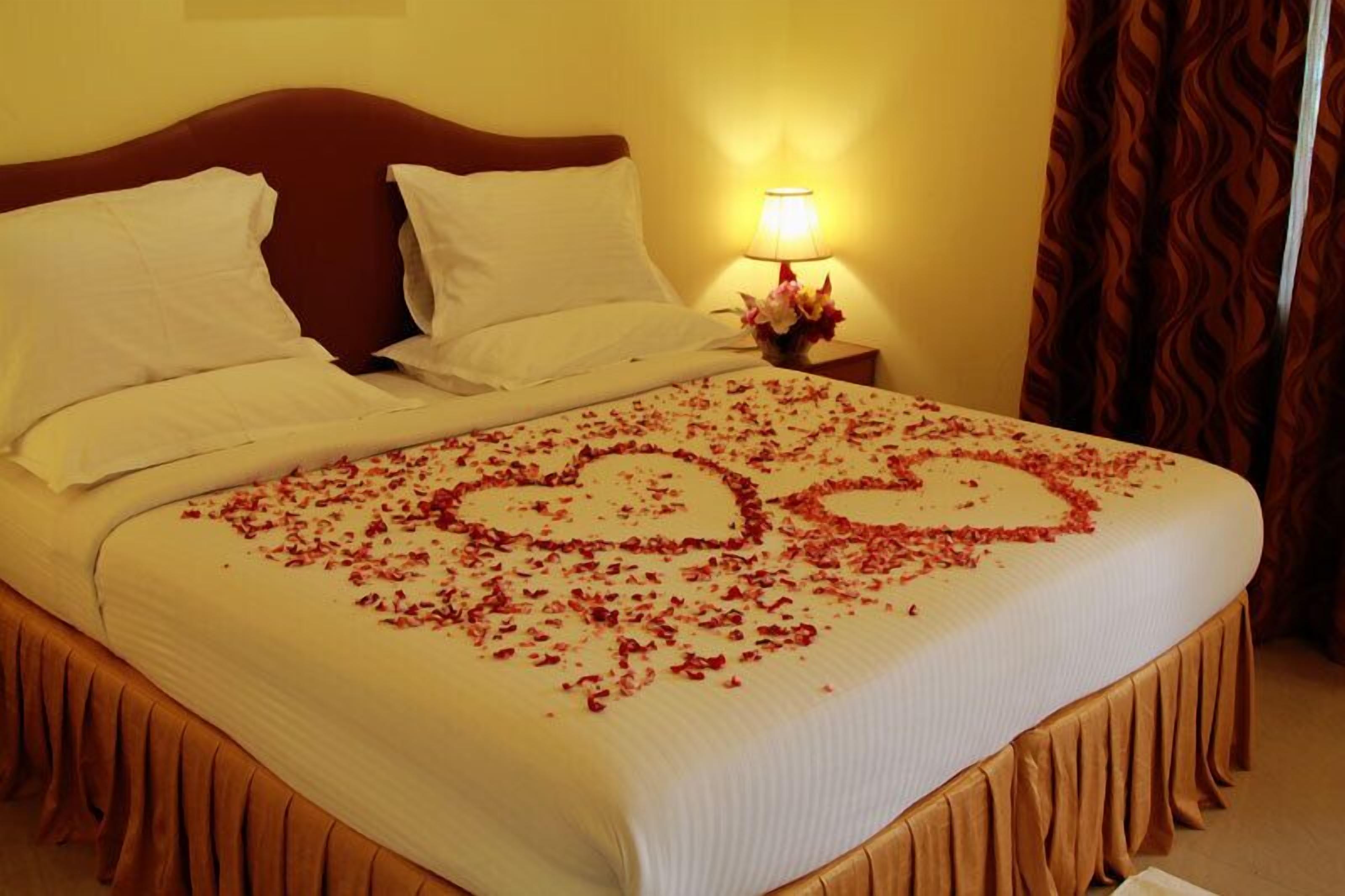Una cama con pétalos de rosa dispuestos en forma de corazón sobre el edredón.