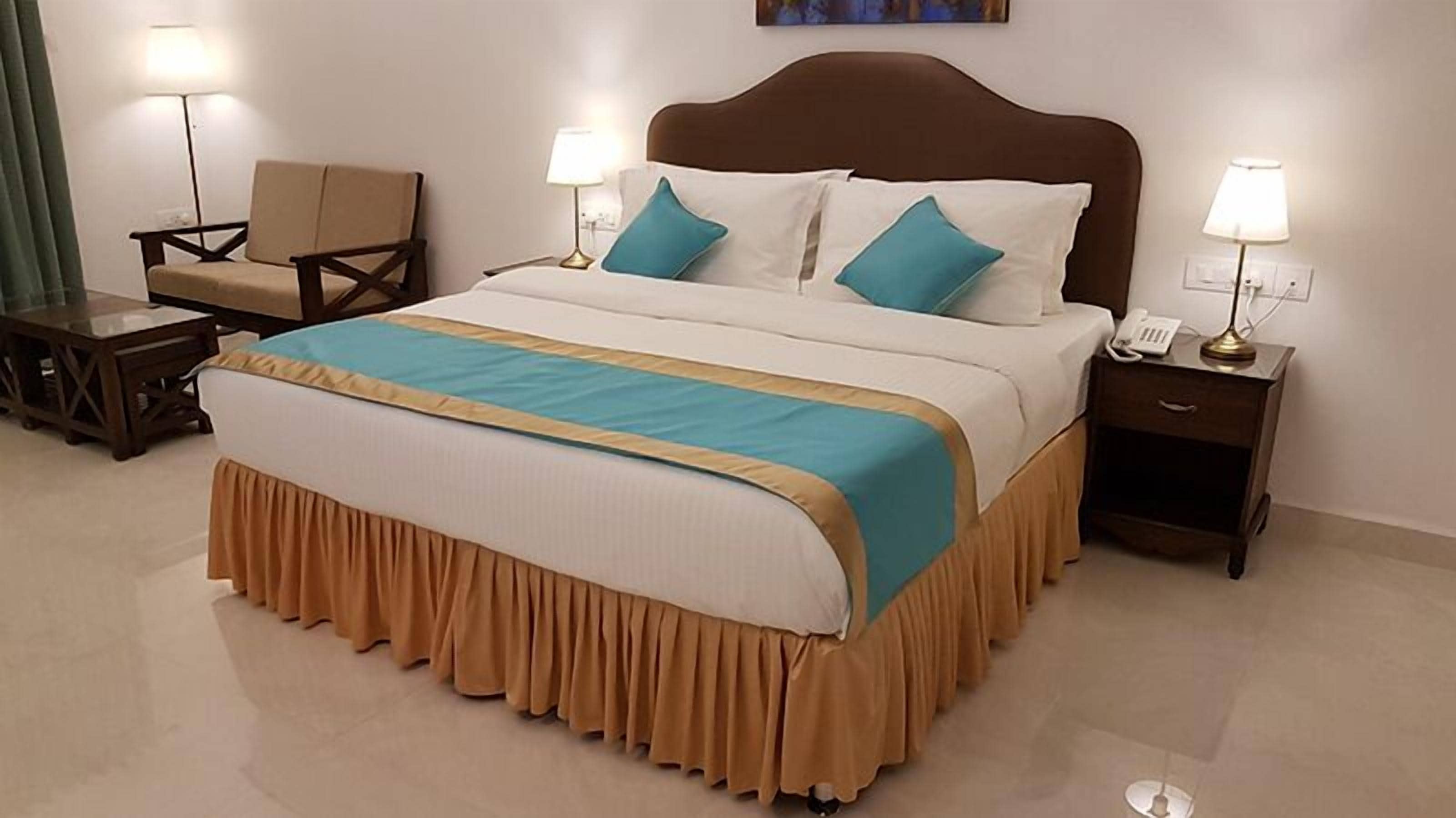 Una habitación de hotel con una cama grande, dos mesitas de noche, una silla y una lámpara de pie.