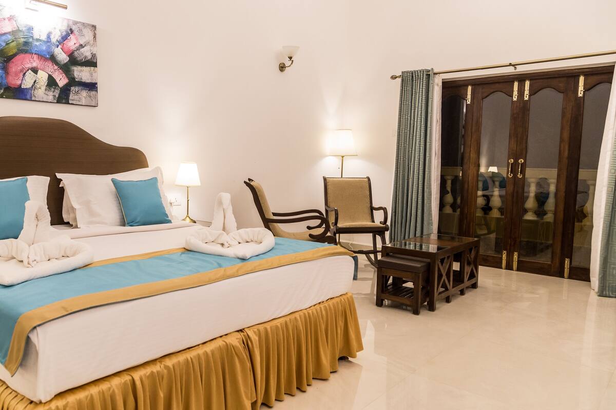 Une chambre d’hôtel avec un grand lit, une chaise, une table et un tableau au mur.