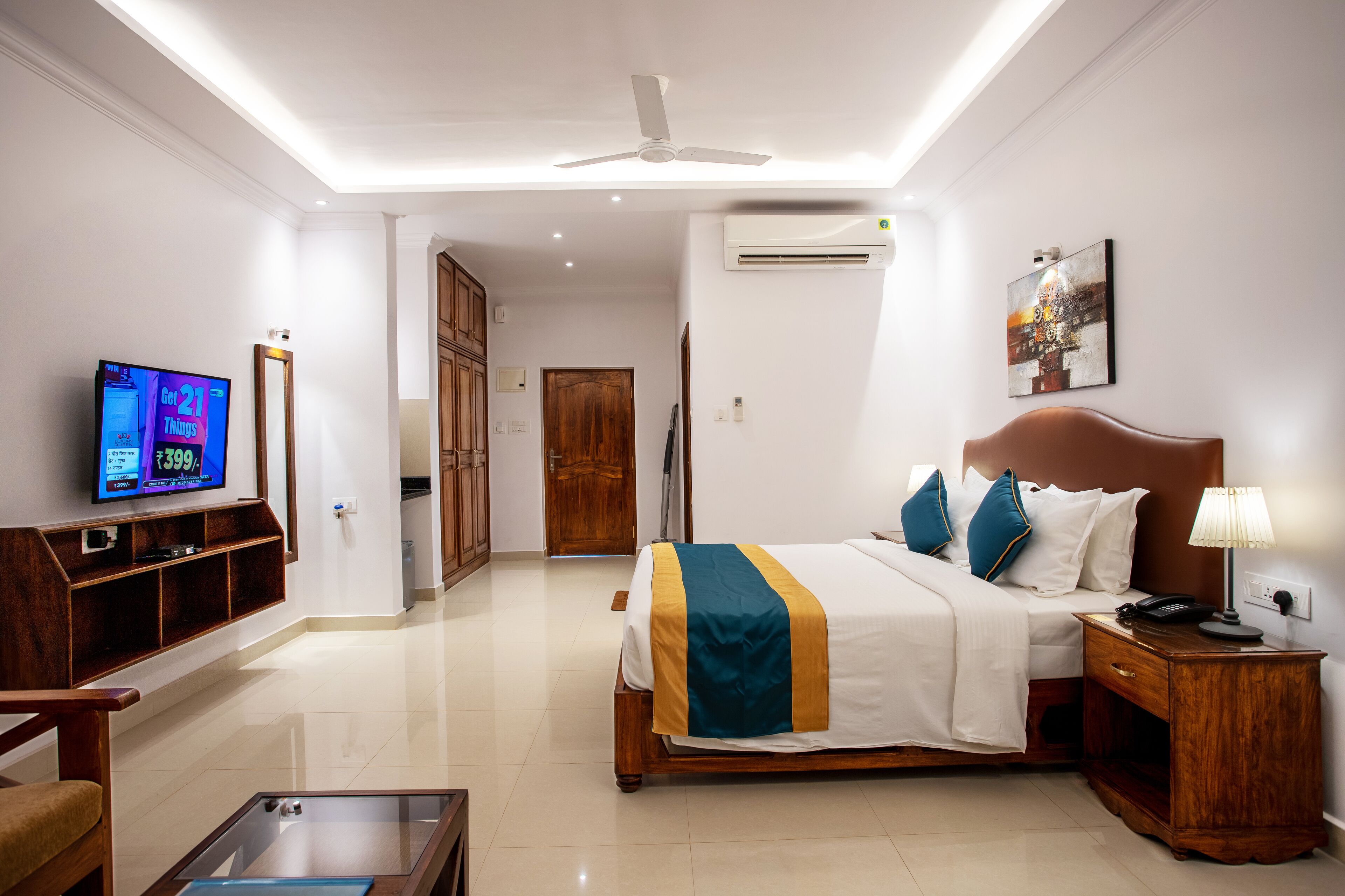 A hotel room with a bed, bedside table, TV, and a wooden cabinet.