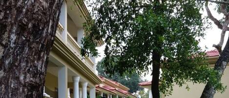 A pathway leading to a building with columns and a red roof.
