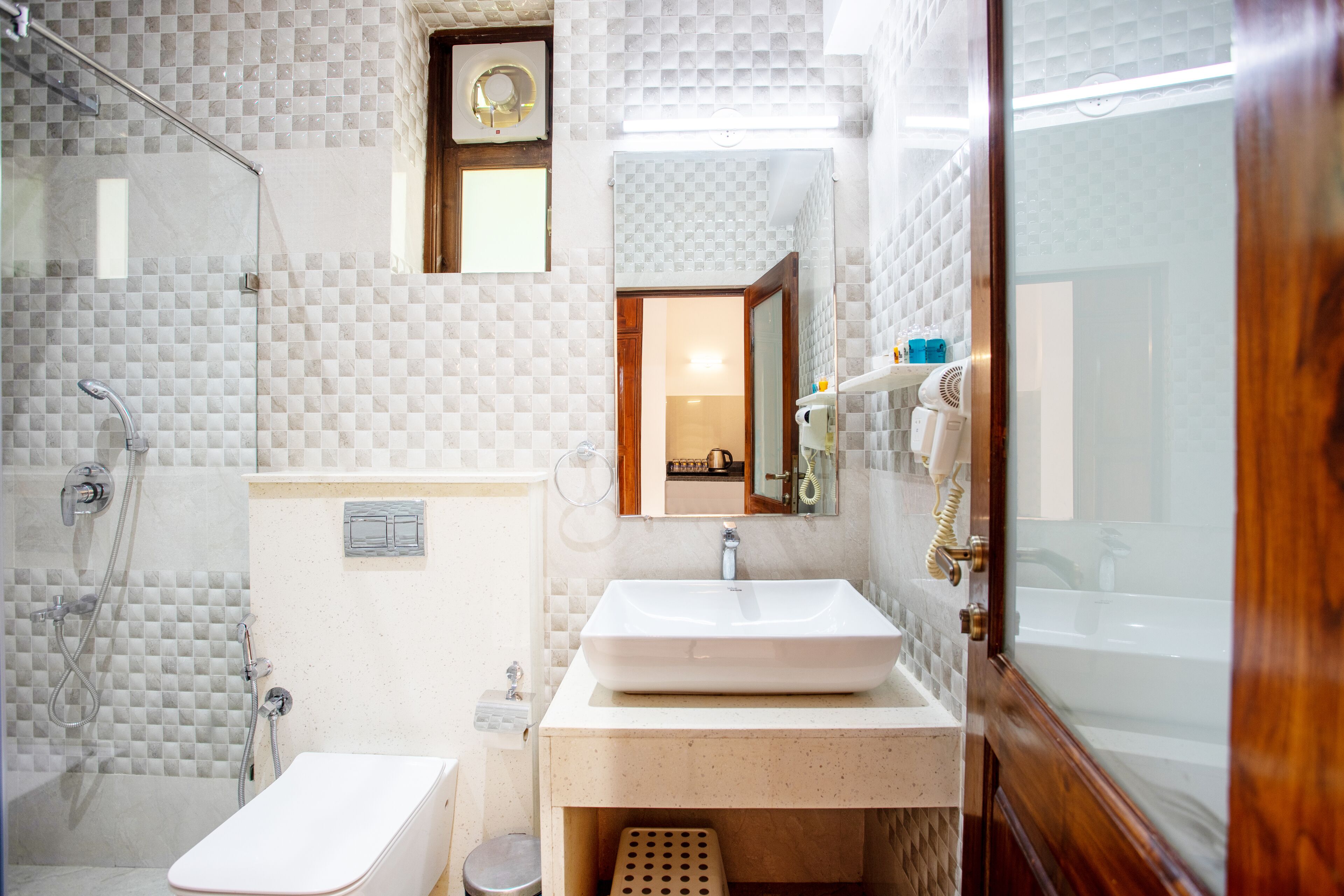 A bathroom with a shower, toilet, sink, and mirror.