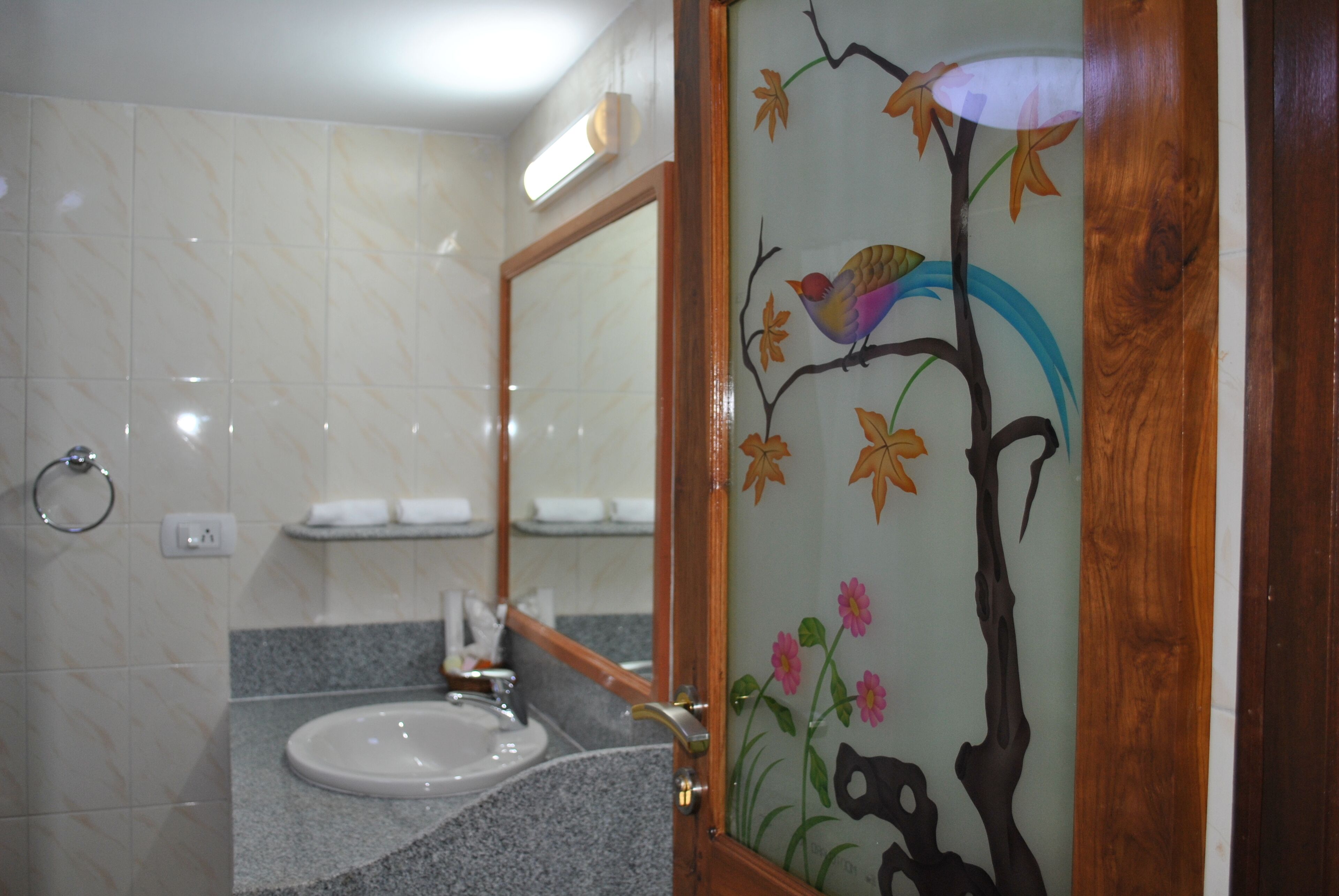A bathroom with a marble wall, a sink, and a mirror with a wooden frame.