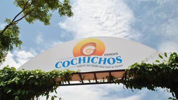 A sign for the Cochichos resort with a clear sky in the background.