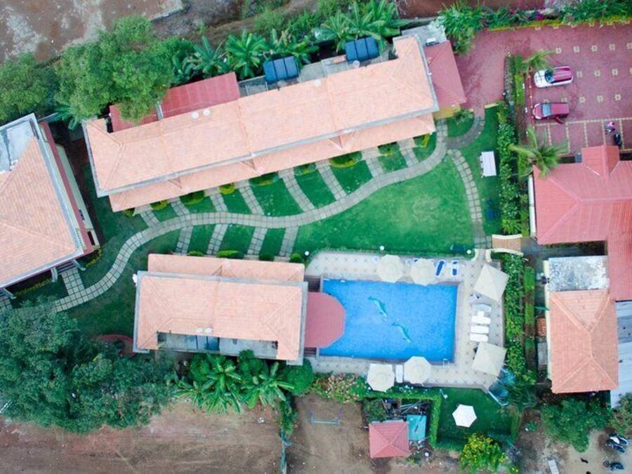An aerial view of a resort with multiple buildings, a swimming pool, and surrounding greenery.