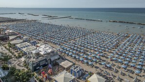 Une plage avec de nombreux parasols et quelques bâtiments en arrière-plan.