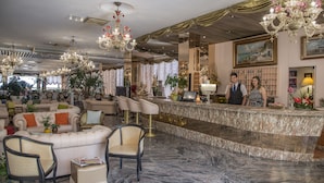 Un hall d’entrée luxueux, doté d’un sol en marbre, d’élégants lustres, de fauteuils confortables et d’un comptoir d’accueil.