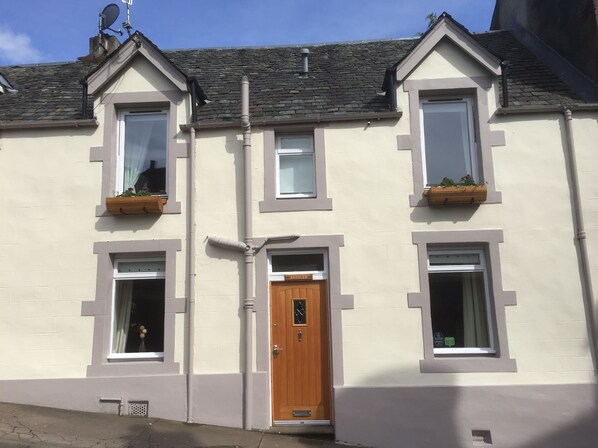 A two-story building with a central wooden door, two windows on each floor, and a satellite dish on the roof. - Avonlea (Crieff)