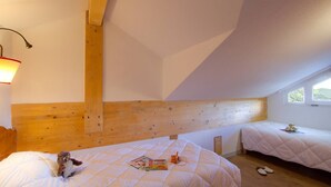 Quarto com duas camas, cabeceira de madeira, uma janela e uma luminária.