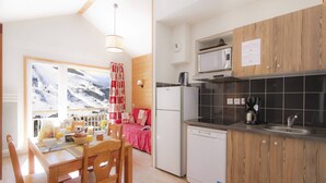 Cozinha compacta com geladeira, micro-ondas e lava-louças.
